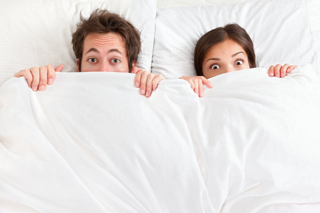 couple in bed looking worried about toxins